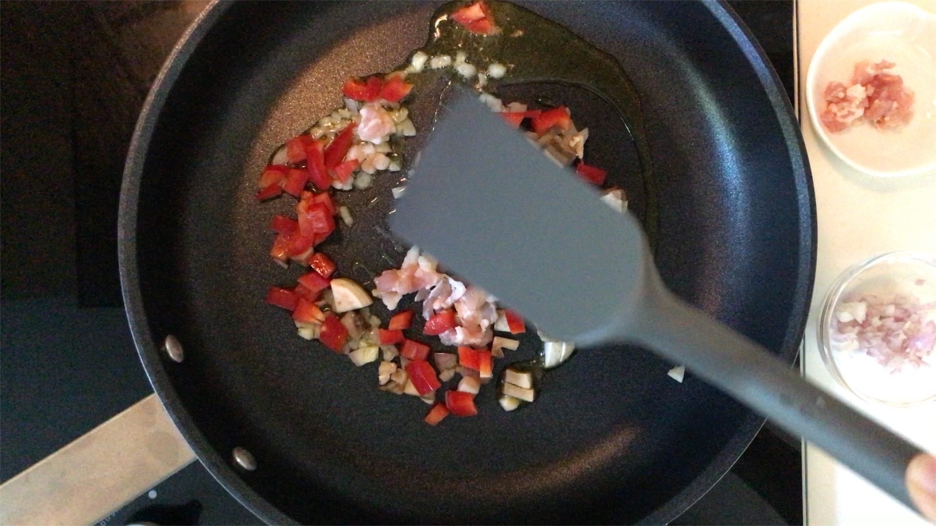 stir frying chopped shallot, bacon, mushroom and red bell pepper in a pan with olive oil