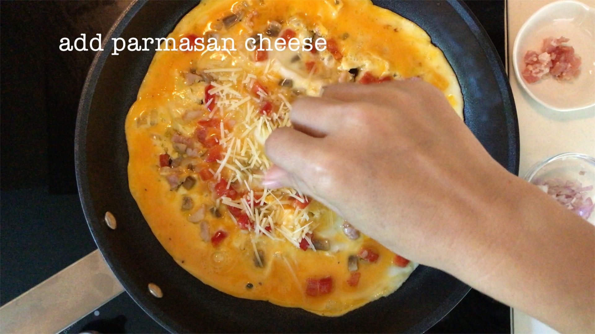 sprinkling some grated Parmesan cheese on the uncooked omelette
